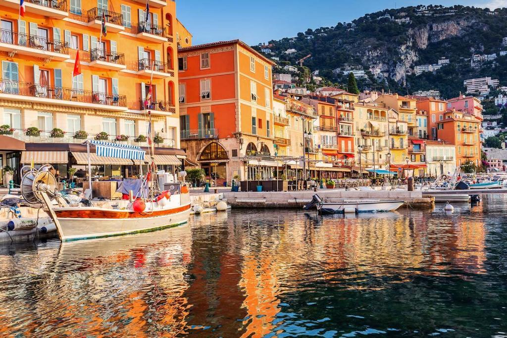 A picture of the coastal area of Villefranche-Sur-Mer with boats, the ocean, restaurants, hotels and more