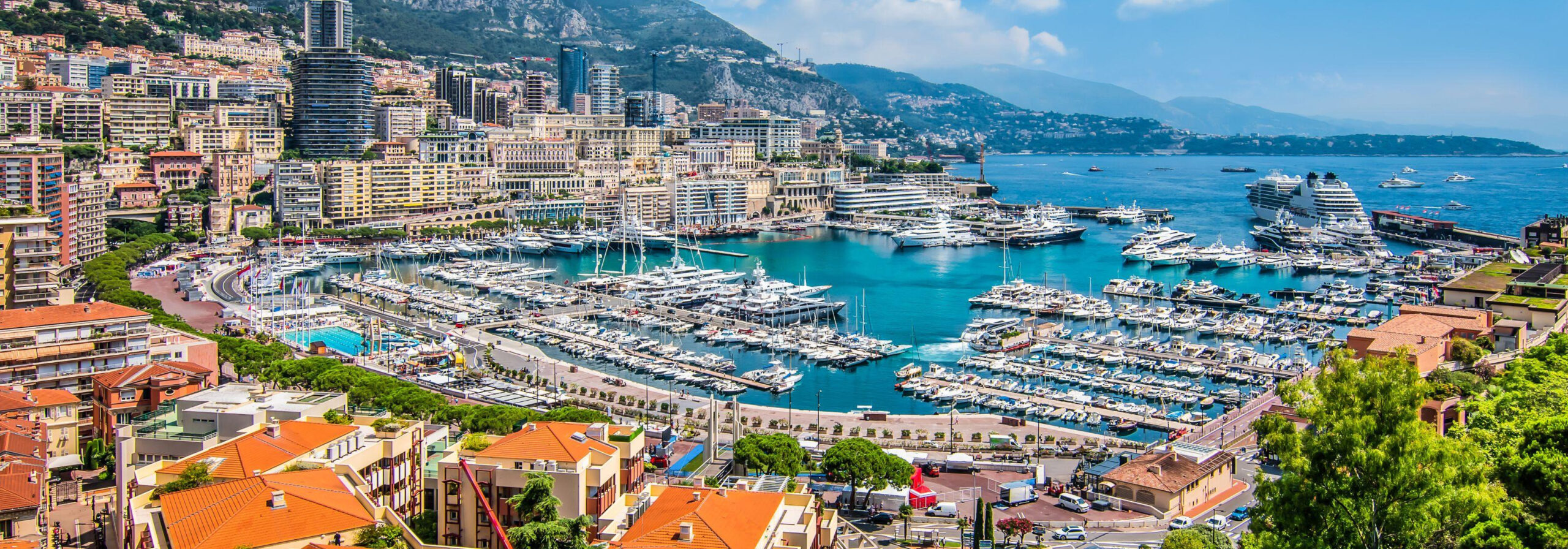 A photo of Port Hercule in Monaco. In this photo you see the skyline of Monaco with a mixture of Superyachts, Residential Buildings, Offices, Museums and more overlooking the Mediterranean sea and mountains.
