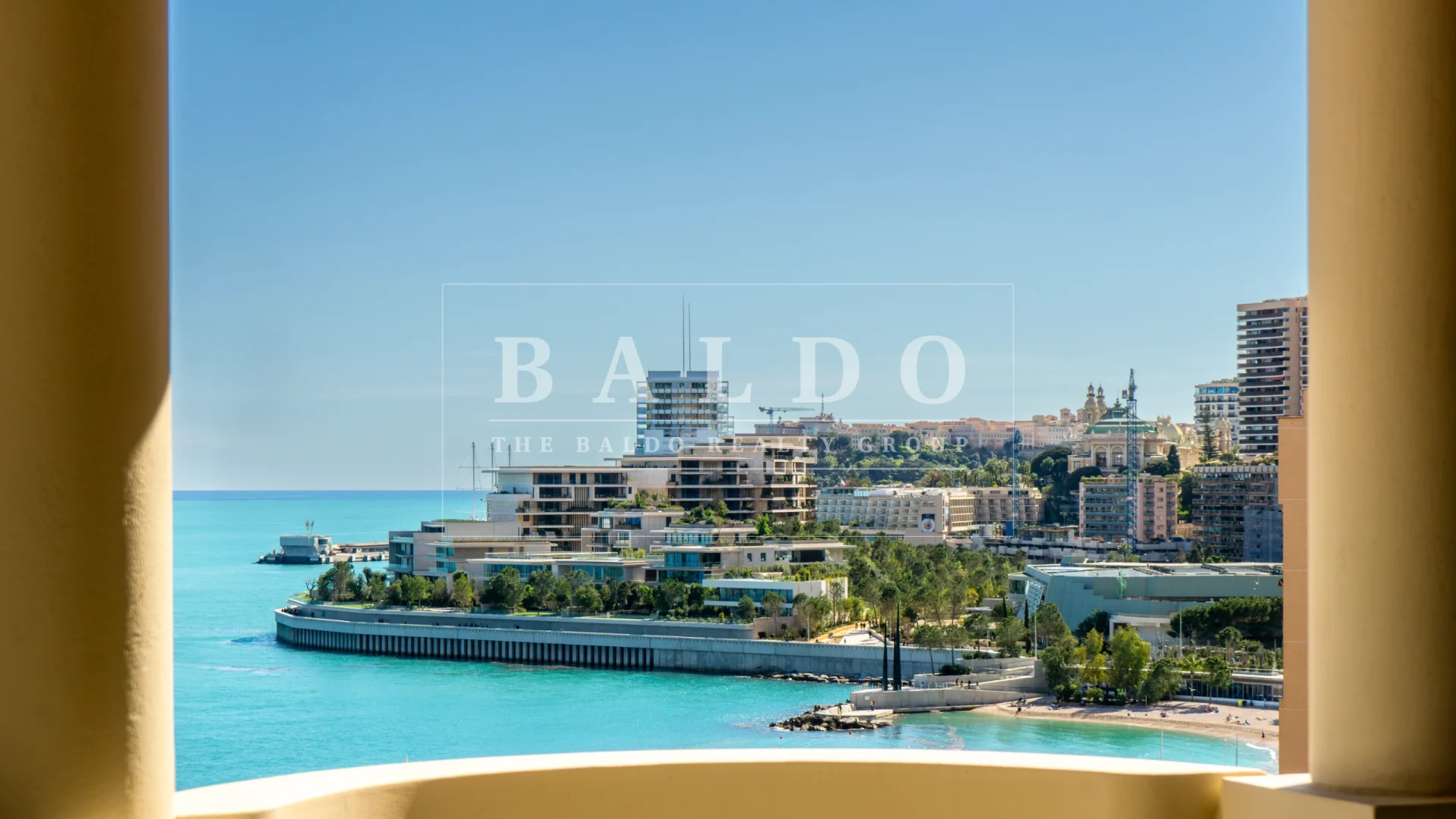 A photo of Larvotto Beach and Mareterra Monaco. In this photo you see the beach and houses with the pillars from the Floristan residence on each side of the photo.