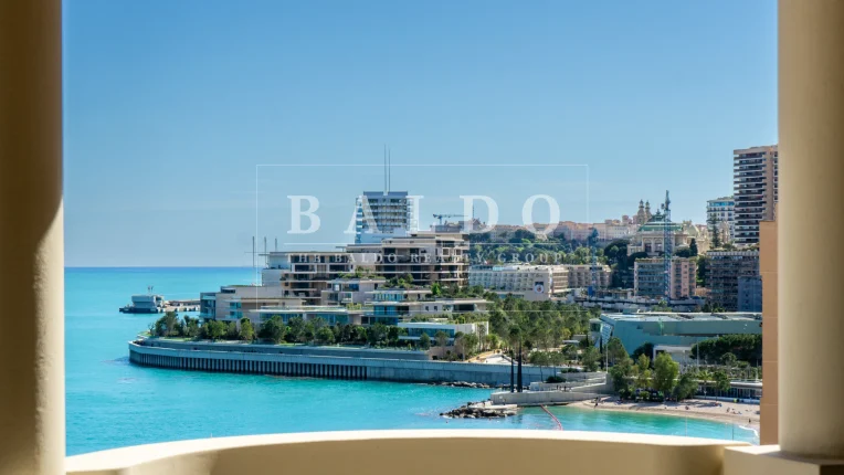 A photo of Larvotto Beach and Mareterra Monaco. In this photo you see the beach and houses with the pillars from the Floristan residence on each side of the photo.