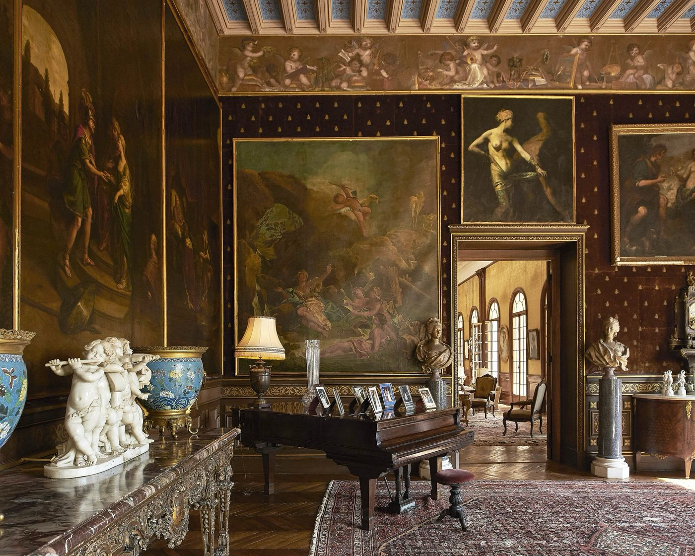 Reception room inside Villa Les Cèdres with piano and historical artwork
