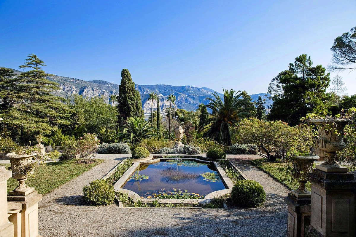 Formal grounds of Villa Les Cèdres with ornamental pond and Maritime Alps in the background