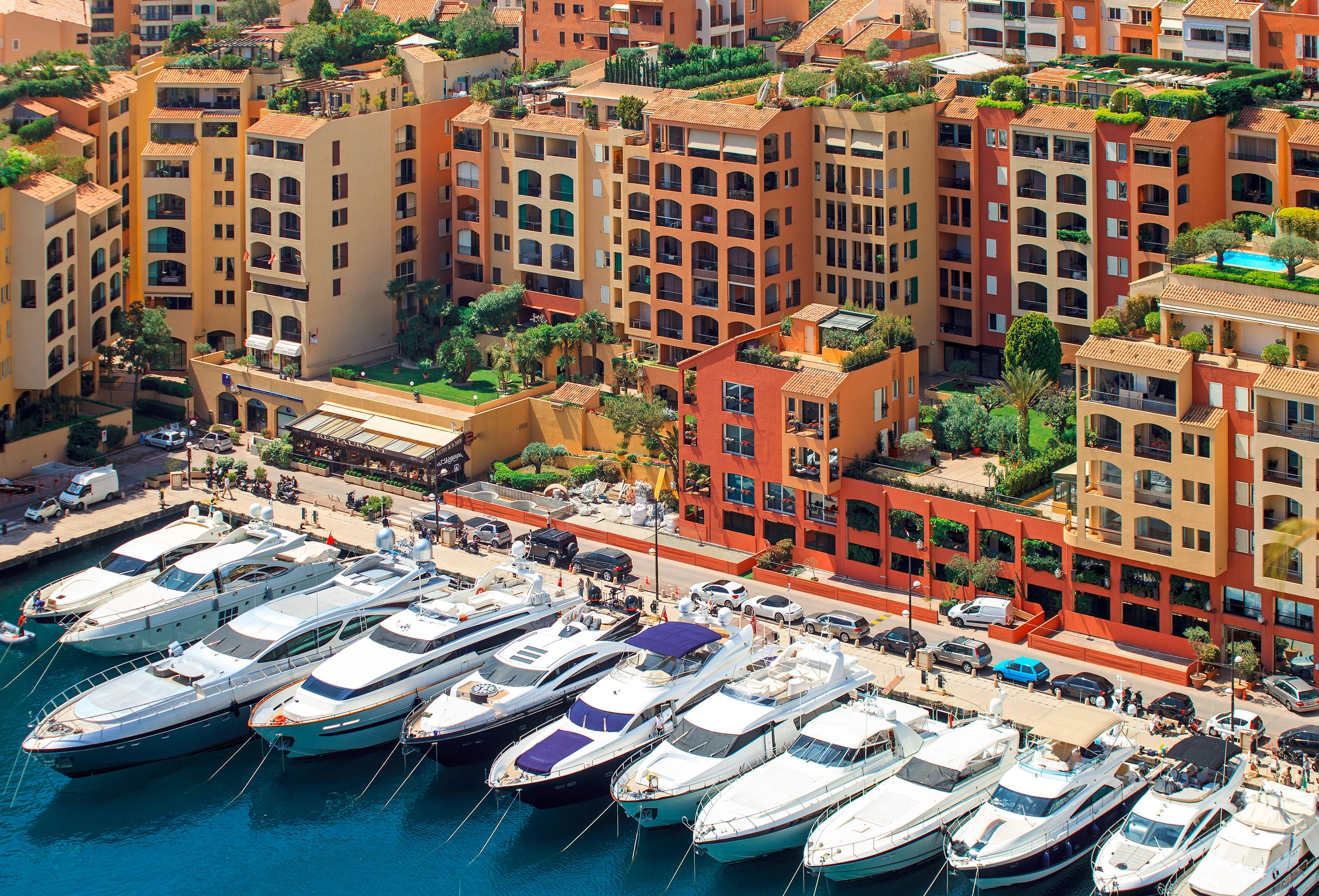 A photo of the rear edge of the port of Fontvieille with a line of superyachts in front of the residences Giorgione, Raphael, and Monte Marina